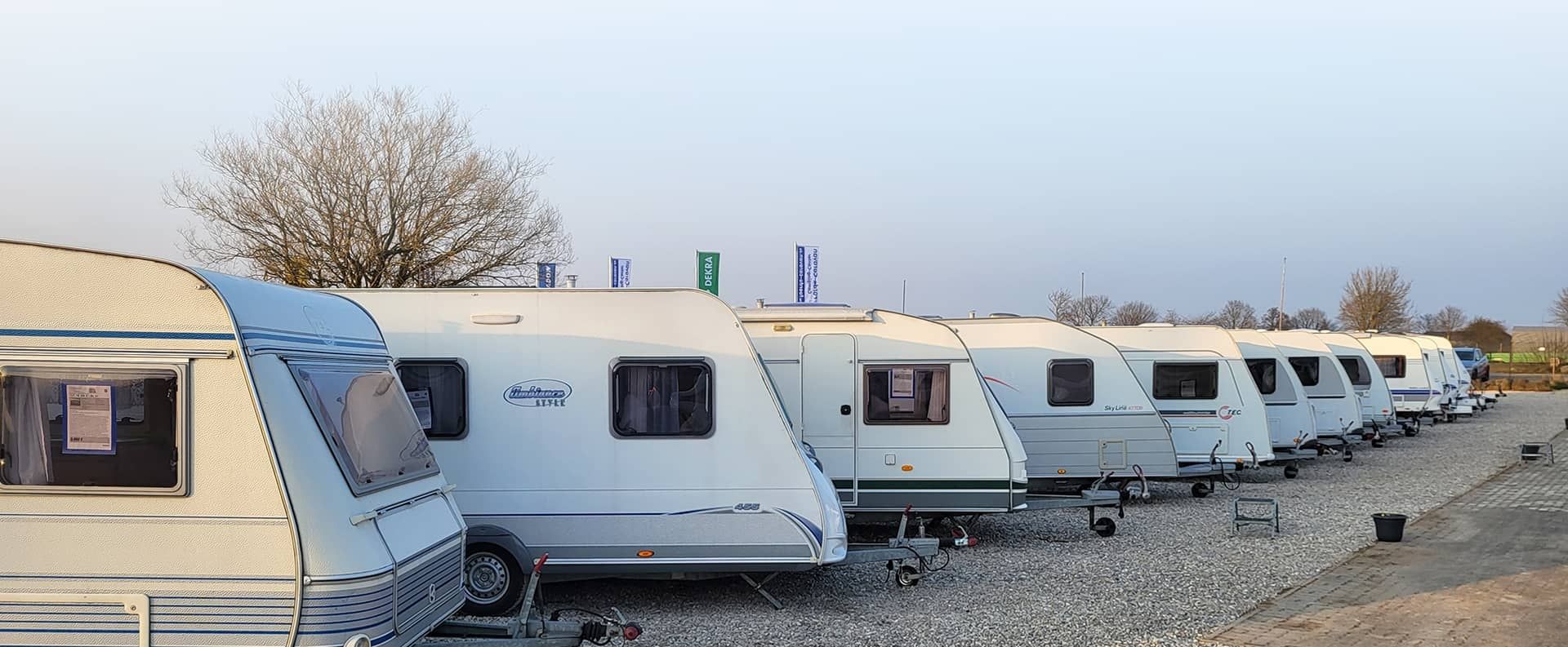 Reihe von Wohnwagen auf einem Schotterplatz unter klarem Himmel